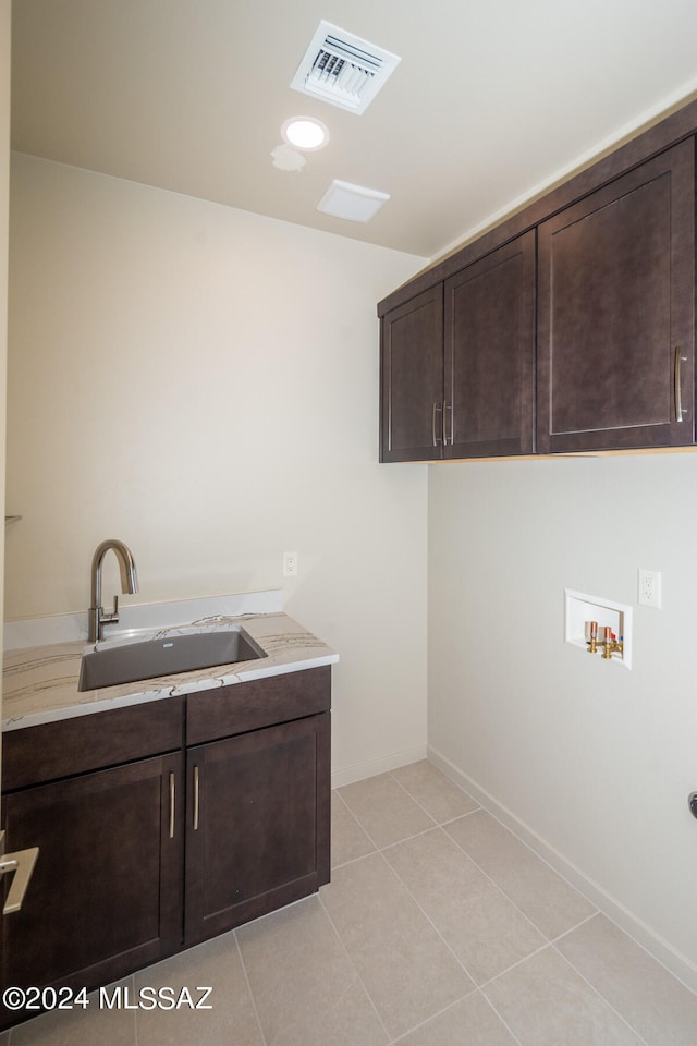 clothes washing area featuring sink, hookup for a washing machine, light tile patterned floors, and cabinets