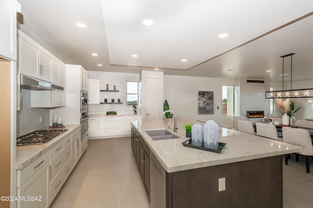 kitchen featuring a large island with sink, sink, white cabinetry, and stainless steel gas stovetop