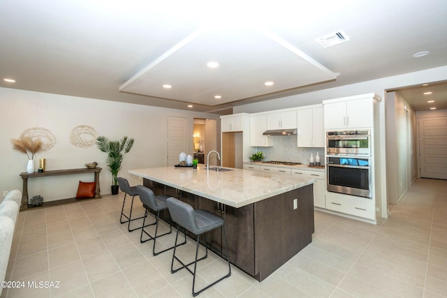 kitchen with white cabinets, a spacious island, a kitchen breakfast bar, stainless steel appliances, and sink