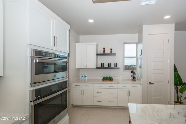 kitchen with stainless steel double oven, white cabinets, and light stone counters