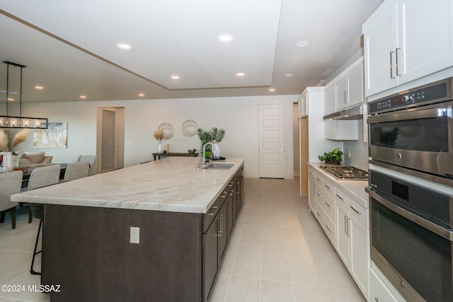 kitchen with appliances with stainless steel finishes, white cabinetry, sink, and a center island with sink