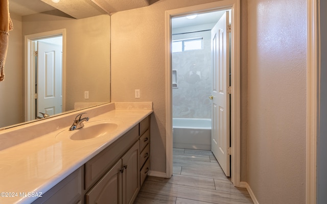 bathroom with vanity, a tub to relax in, a textured ceiling, and hardwood / wood-style floors