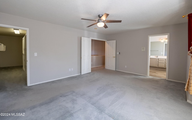 unfurnished bedroom with connected bathroom, a textured ceiling, carpet floors, and ceiling fan