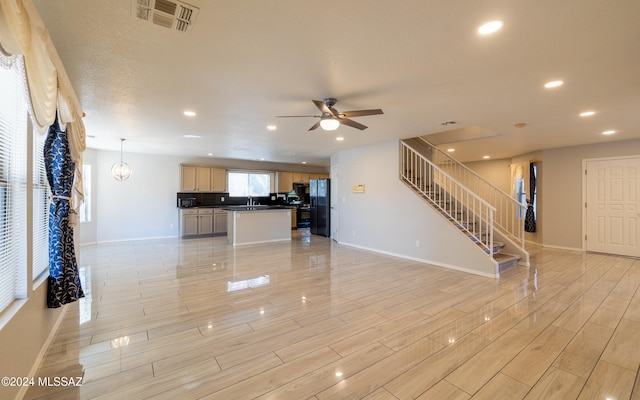 unfurnished living room with sink, light hardwood / wood-style flooring, and ceiling fan with notable chandelier