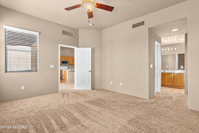 unfurnished bedroom with light carpet, connected bathroom, and ceiling fan