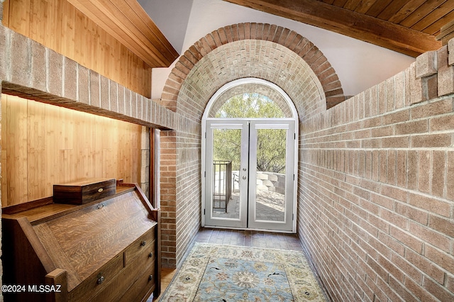 entryway featuring vaulted ceiling with beams, french doors, brick wall, and light hardwood / wood-style floors