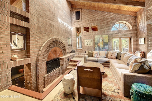 living room featuring beam ceiling, high vaulted ceiling, wood ceiling, and brick wall