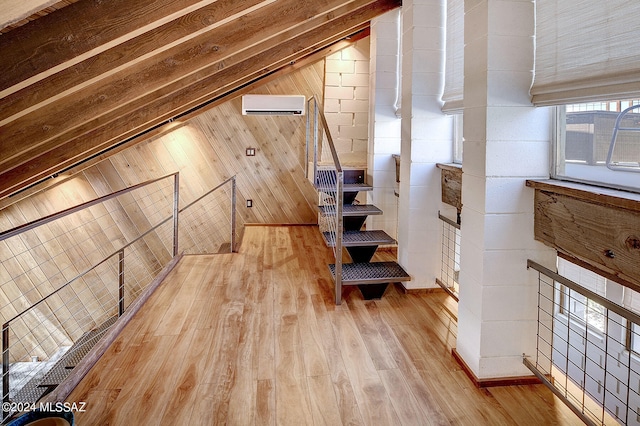 additional living space with lofted ceiling, an AC wall unit, wood-type flooring, and wooden walls