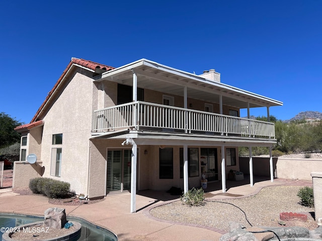 rear view of house featuring a patio and a balcony