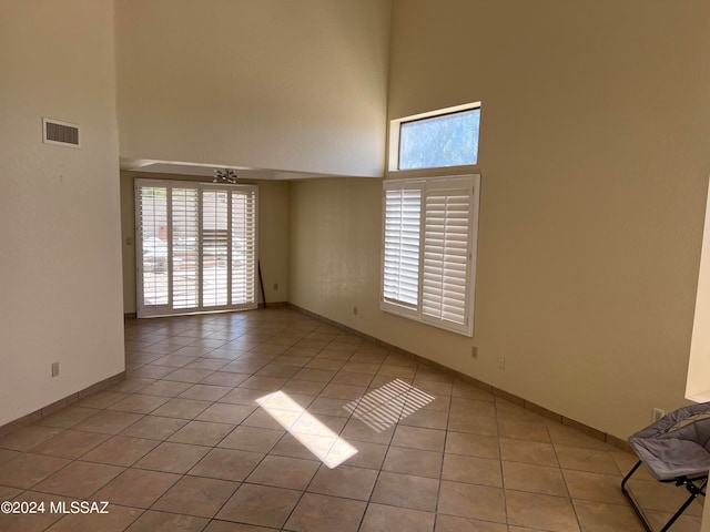 empty room with a high ceiling and light tile patterned floors