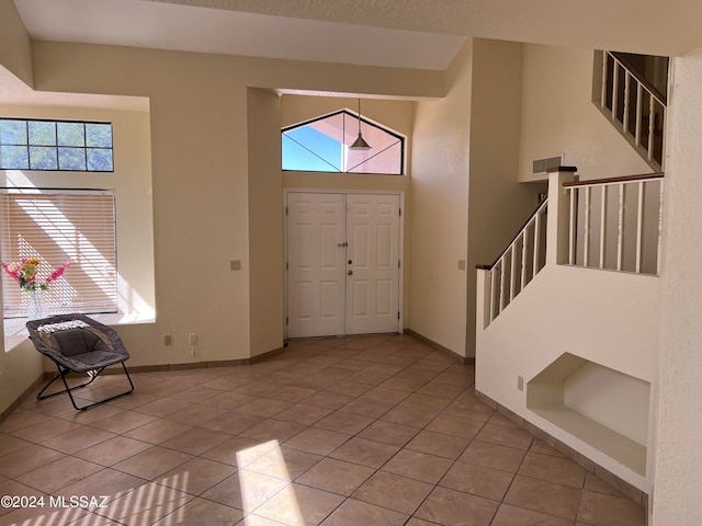 tiled entrance foyer featuring a high ceiling and plenty of natural light