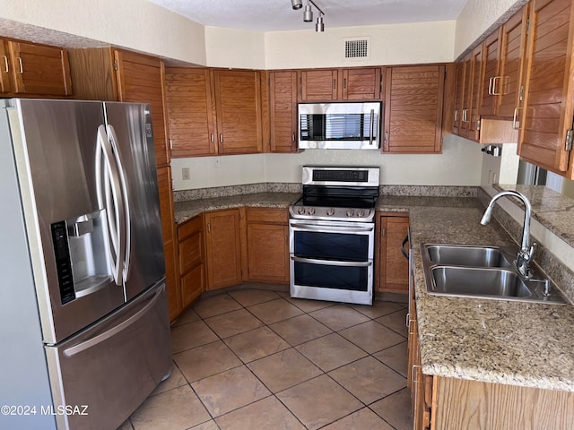 kitchen featuring sink, stainless steel appliances, a textured ceiling, and light tile patterned floors