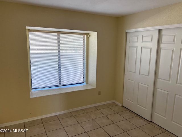 unfurnished bedroom with a closet and light tile patterned floors