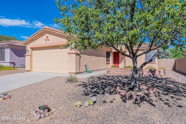 view of front of property with a tiled roof, driveway, fence, a garage, and stucco siding