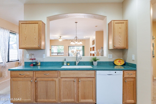 kitchen featuring light brown cabinetry, dark countertops, a sink, white dishwasher, and ceiling fan with notable chandelier