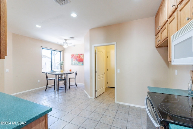 kitchen featuring light tile patterned flooring, stove, light brown cabinetry, and ceiling fan