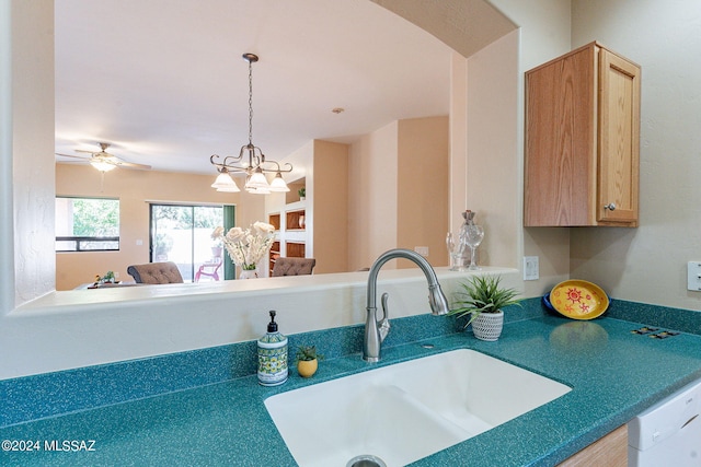 kitchen featuring arched walkways, a sink, ceiling fan with notable chandelier, white dishwasher, and decorative light fixtures