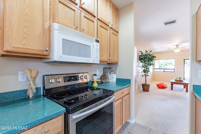 kitchen with ceiling fan, light brown cabinetry, light tile patterned floors, and stainless steel range with electric cooktop