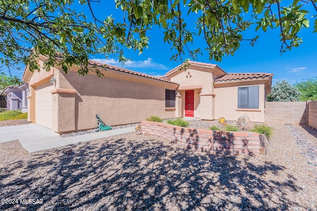 mediterranean / spanish house featuring stucco siding, an attached garage, fence, and a tile roof