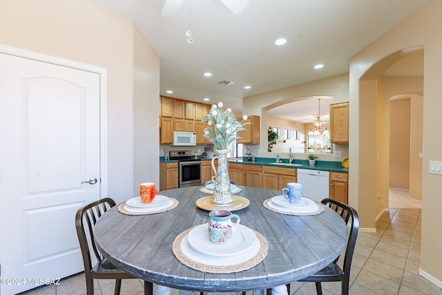 dining area featuring recessed lighting, visible vents, light tile patterned floors, arched walkways, and ceiling fan with notable chandelier