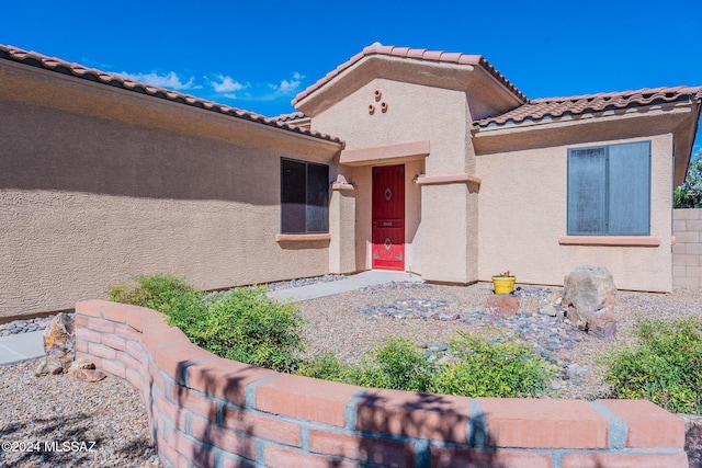 doorway to property with a tiled roof and stucco siding