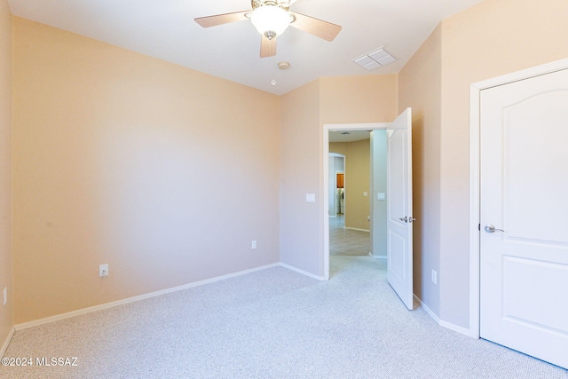 spare room featuring baseboards, a ceiling fan, visible vents, and light colored carpet
