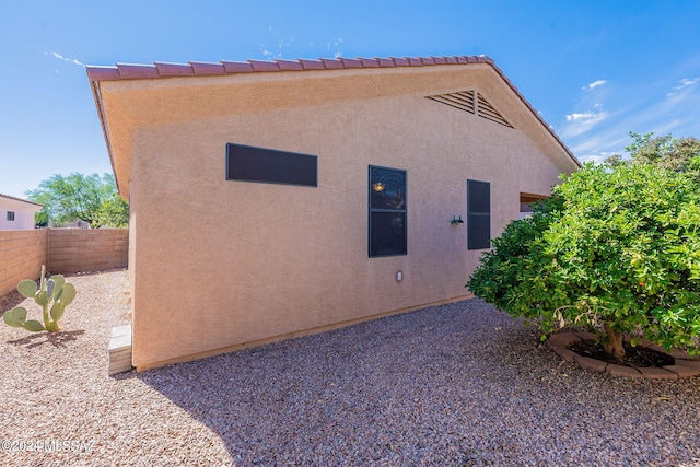 view of side of property with stucco siding and fence