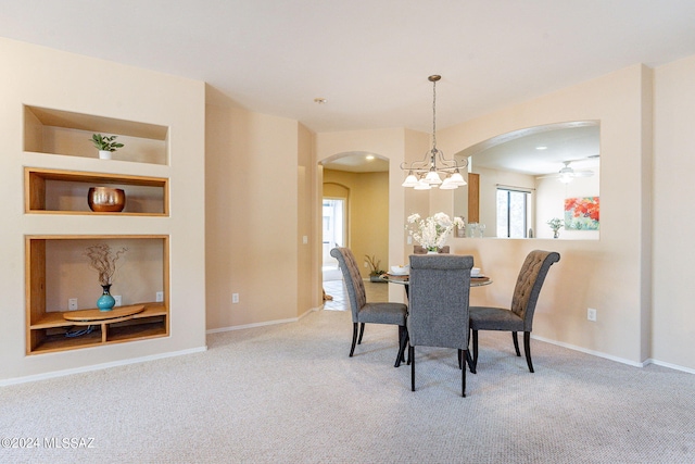 dining room with a chandelier, arched walkways, carpet floors, built in features, and baseboards
