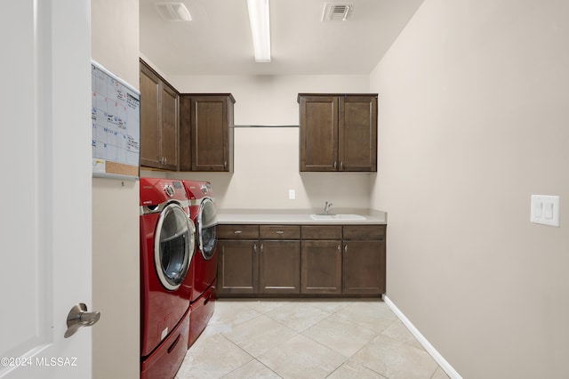 laundry area with sink, light tile patterned flooring, washing machine and clothes dryer, and cabinets