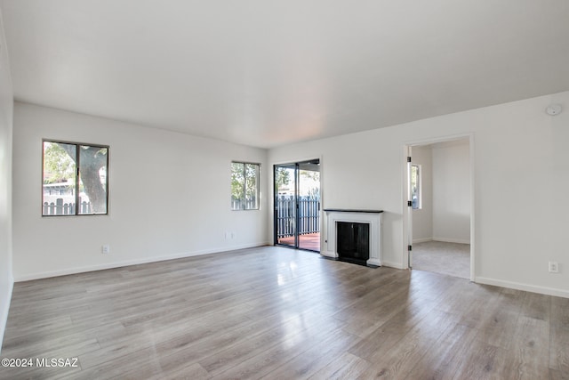 unfurnished living room featuring light wood-type flooring and a healthy amount of sunlight