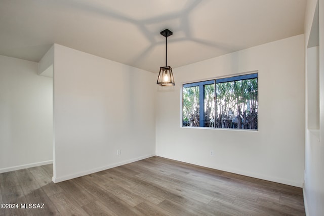 empty room with hardwood / wood-style floors and vaulted ceiling