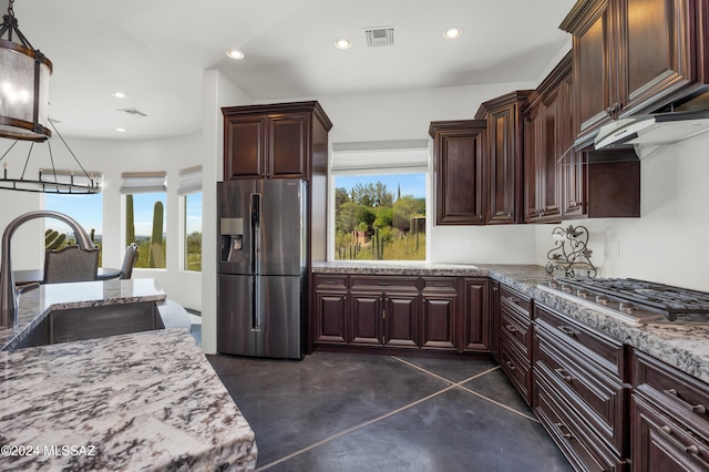 kitchen with light stone counters, sink, pendant lighting, a notable chandelier, and stainless steel appliances