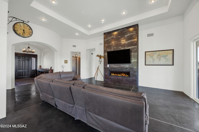 living room with a towering ceiling, a fireplace, and a tray ceiling