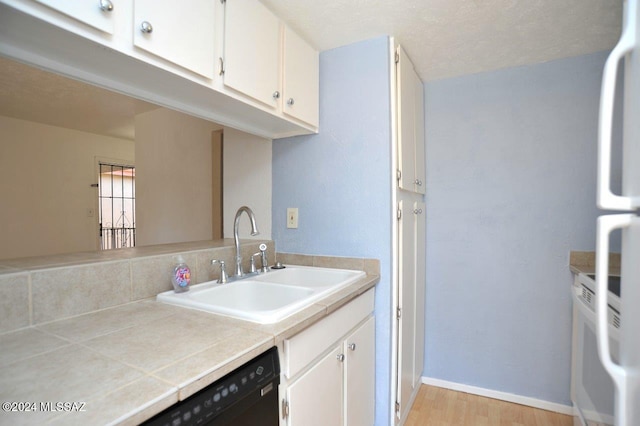 kitchen with tile countertops, white cabinets, sink, and light wood-type flooring