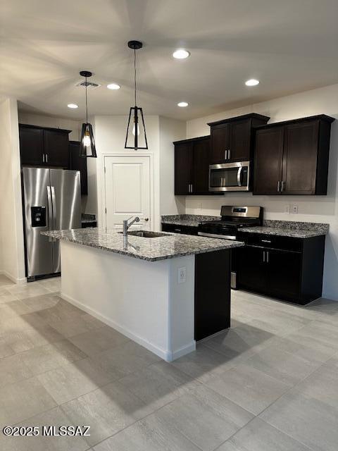 kitchen featuring appliances with stainless steel finishes, decorative light fixtures, a center island with sink, and sink