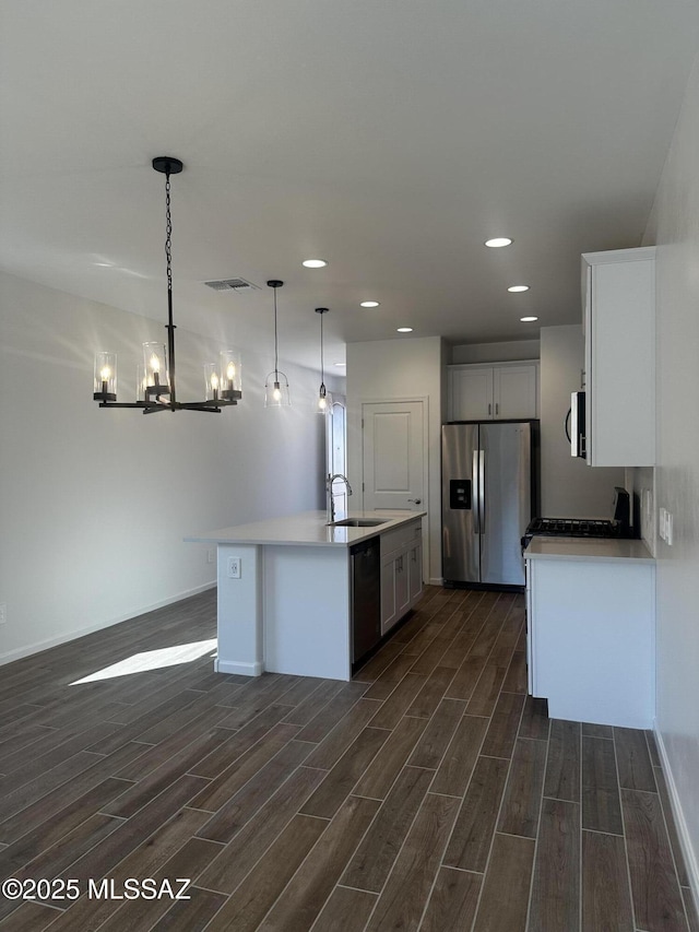 kitchen featuring wood finish floors, stainless steel fridge, visible vents, dishwasher, and a sink