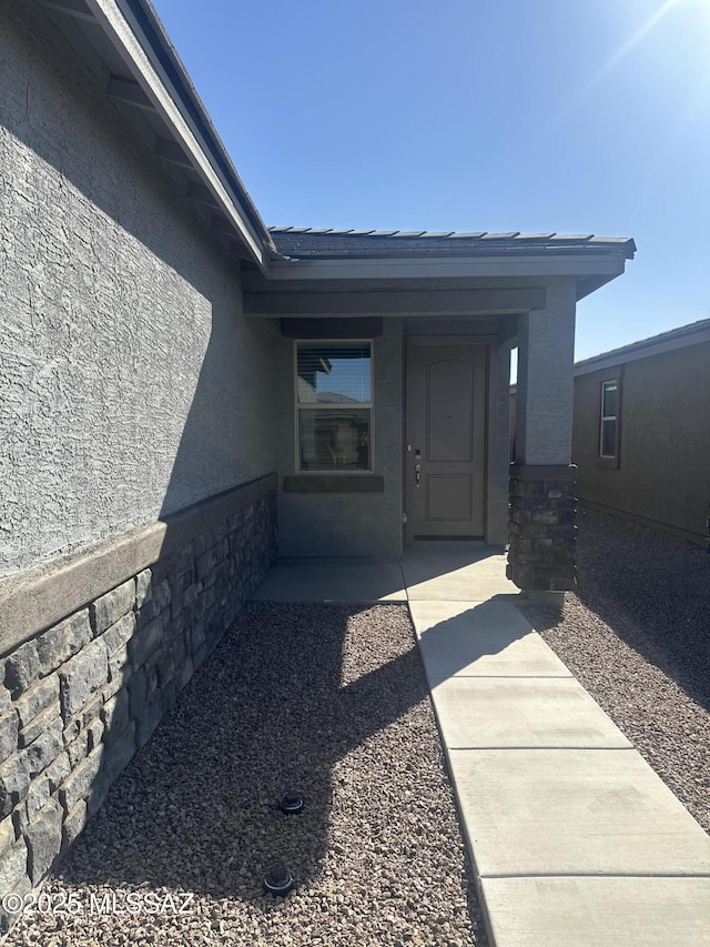 view of exterior entry with stucco siding and stone siding