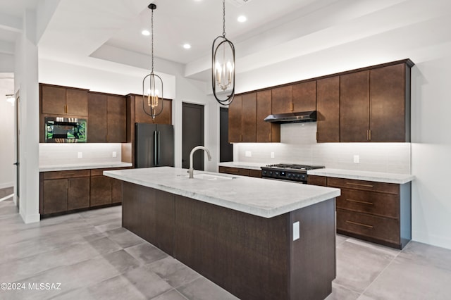 kitchen with stainless steel appliances, dark brown cabinets, sink, and a center island with sink