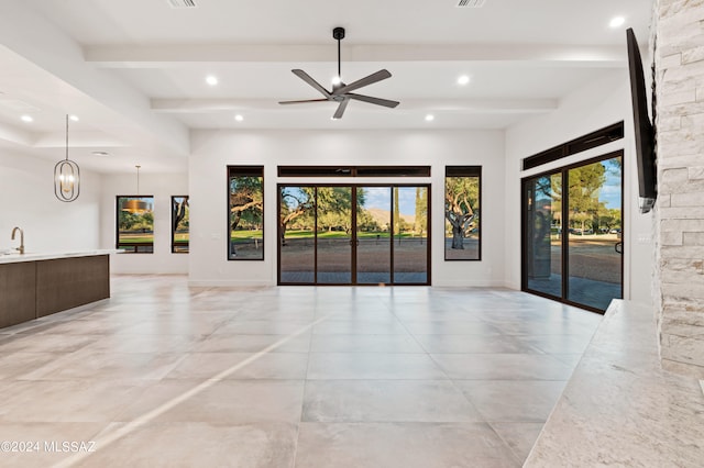 unfurnished living room with ceiling fan, beamed ceiling, and sink