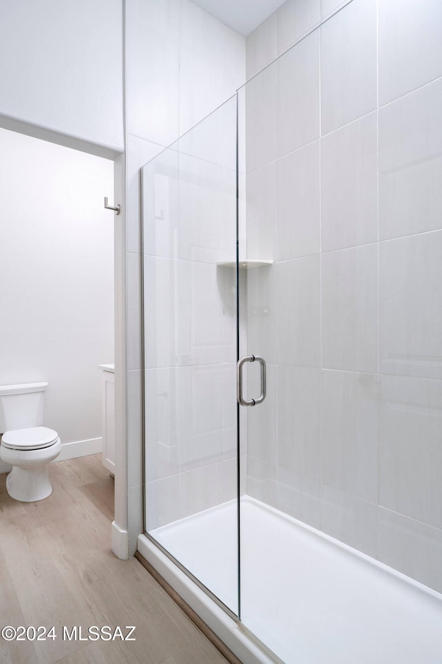 bathroom with toilet, hardwood / wood-style flooring, and a shower with shower door