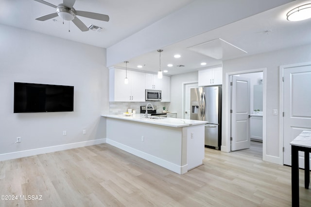 kitchen featuring stainless steel appliances, white cabinetry, kitchen peninsula, decorative light fixtures, and light wood-type flooring