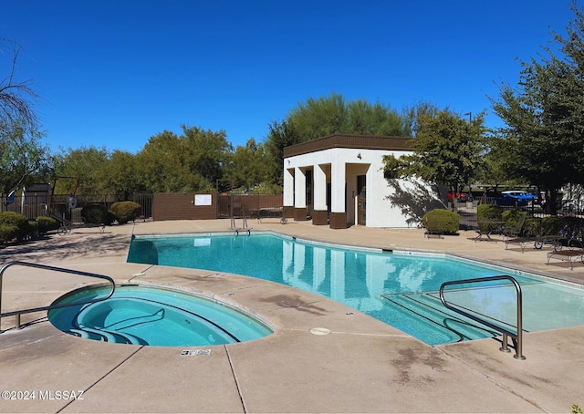 view of swimming pool featuring a hot tub and a patio area