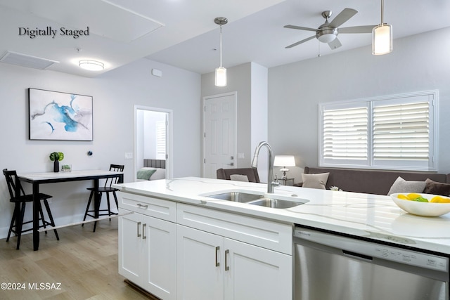 kitchen with decorative light fixtures, stainless steel dishwasher, sink, and white cabinets