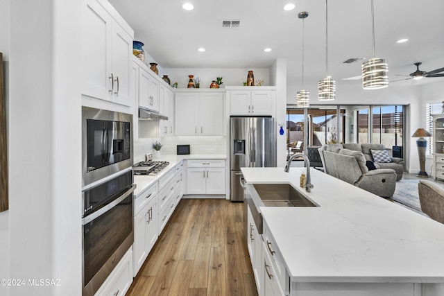 kitchen featuring white cabinetry, ceiling fan, hanging light fixtures, stainless steel appliances, and light hardwood / wood-style floors