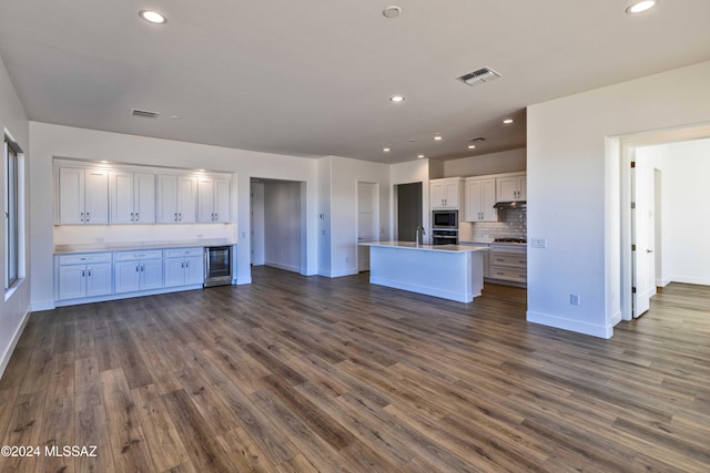 kitchen featuring a center island with sink, white cabinetry, dark wood-type flooring, and appliances with stainless steel finishes