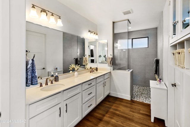 bathroom featuring hardwood / wood-style flooring, vanity, and a tile shower