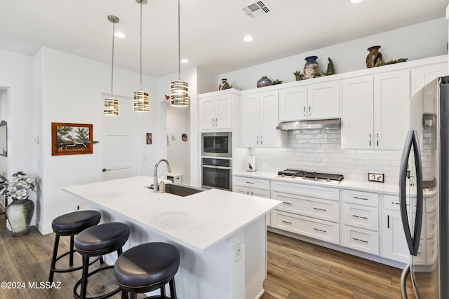 kitchen with dark hardwood / wood-style flooring, stainless steel appliances, a center island with sink, and sink