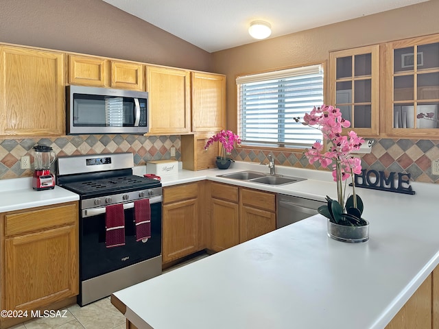 kitchen with tasteful backsplash, sink, light tile patterned flooring, stainless steel appliances, and vaulted ceiling