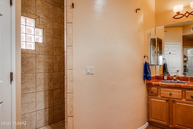 bathroom with vanity and tiled shower