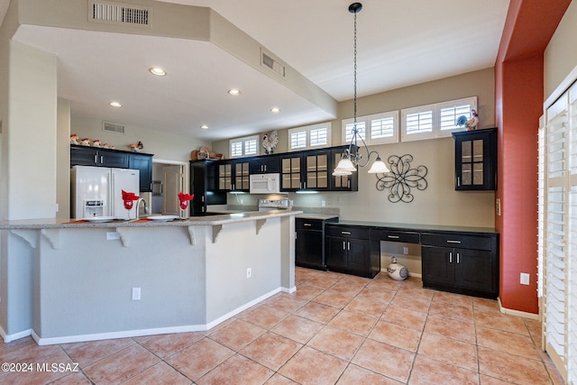 kitchen featuring a breakfast bar, kitchen peninsula, white appliances, and light tile patterned floors